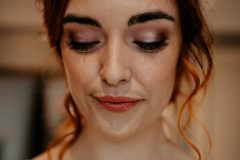 A bride on her wedding morning, wearing a natural makeup look with pink eyeshadow. 