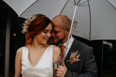 A couple on their wedding day at Vaulty Manor holding an umbrella.